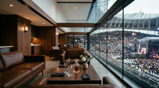 Vue grand angle d'une loge VIP luxueuse avec terrasse privée surplombant une scène ou un terrain, mettant en valeur l'exclusivité et l'hospitalité haut de gamme