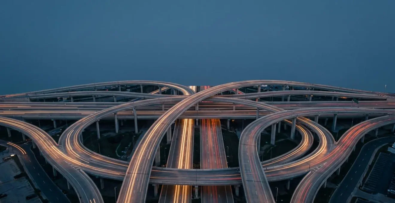Vue aérienne minimaliste d'un échangeur autoroutier urbain au crépuscule avec flux de circulation