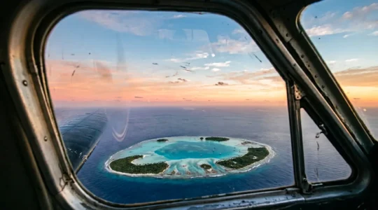 Vue aérienne spectaculaire d'un atoll du Pacifique au lever du soleil depuis un hydravion en approche